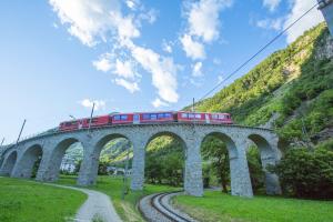a red train on a bridge with a mountain at Casa Piazzo in Brusio