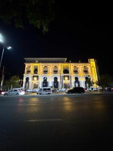 a large yellow building with cars parked in front of it at ASR Plaza in Jizzax
