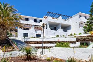 a white building with stairs and a palm tree at Sardina Ocean Front Apartment in Gáldar