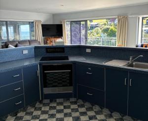 a kitchen with blue cabinets and a sink at Seaside At Stephens Bay in Kaiteriteri