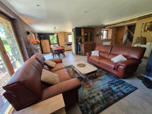 a living room with brown leather couches and a table at Le Petit Marcheloup in Paliseul