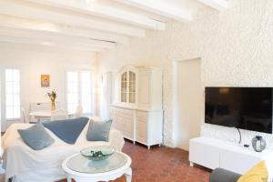 a living room with a white couch and a tv at Moulin de Vigne in Corgnac-sur-lʼIsle