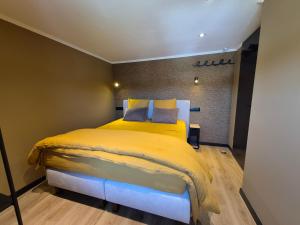 a bedroom with a yellow bed in a room at Le Petit Marcheloup in Paliseul