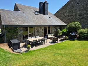 a patio with a table and chairs and a house at Le Petit Marcheloup in Paliseul