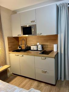 a kitchen with white cabinets and a sink and a microwave at L'Escale d'Armorique 2 in Languidic