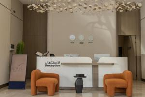a lobby with two orange chairs and a counter at LEGooT HOTEL in Khamis Mushayt