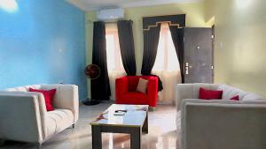 a living room with two couches and a red chair at Awka Dawn Two Bed in Akwa