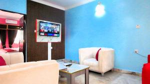a living room with a couch and a tv on a wall at Awka Dawn Two Bed in Akwa
