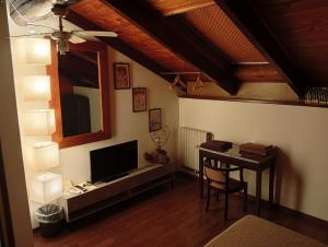 a living room with a television and a table with a chair at Monferrato Inn in Rivarone