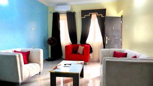 a living room with two white couches and a red chair at Awka Dawn Two Bed in Akwa