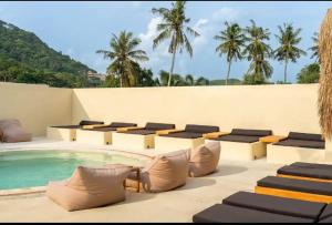 a patio with chairs and a pool and palm trees at Julie House Lombok in Ekas