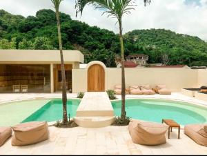 a house with a swimming pool with palm trees at Julie House Lombok in Ekas