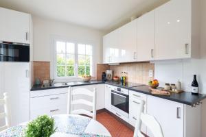 a white kitchen with white cabinets and a table at Moulin de Vigne in Corgnac-sur-lʼIsle
