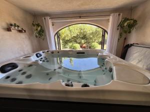a bath tub in a room with a window at Les Coustelines Piscine privée et Jacuzzi in Forcalquier +29 photos