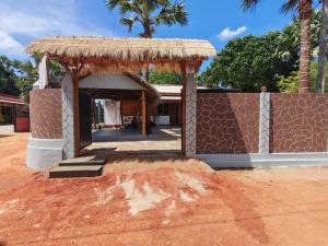 a small building with a straw roof and a wall at Backpackers inn Hostel in Trincomalee