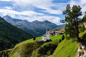 a church on a hill with mountains in the background at Capetta Appartement in Cresta +21 photos
