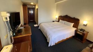 a hotel room with a bed and a flat screen tv at Spring Hotel in Jiaoxi