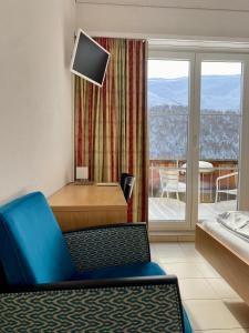 a living room with a blue chair and a balcony at Capetta Appartement in Cresta