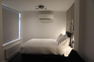 a white bed in a room with a window at Paddington Townhouse Hotel by OYO in London