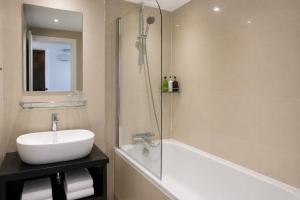 a bathroom with a tub and a sink and a shower at Paddington Townhouse Hotel by OYO in London