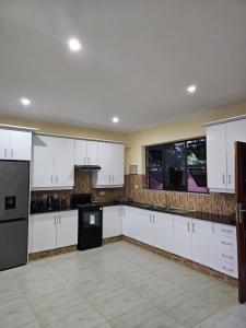 a large kitchen with white cabinets and black appliances at Nyanja Cottage in Chembe