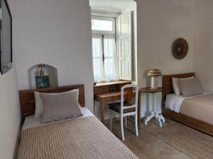 a bedroom with two beds and a desk and a window at Leonidas house hydra in Hydra