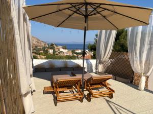 a table and chairs under an umbrella on a patio at Leonidas house hydra in Hydra