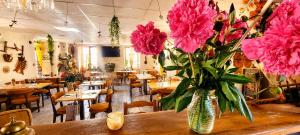 a vase of pink flowers on a table in a restaurant at Auberge du fromager in Saint-Didier-sur-Doulon