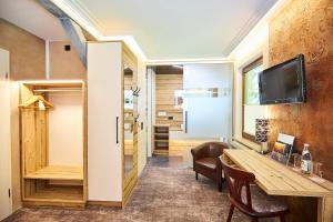 a room with a table and a tv on a wall at Flair-Waldhotel Mellestollen in Saalfeld