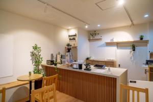 a kitchen with a counter and a table and chairs at Bonsai Cafe and Stay - B&B Dormitory in Tokyo