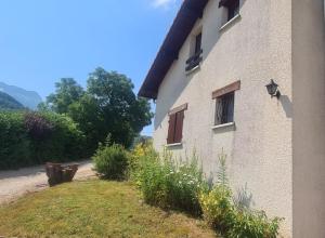 a building with a grass yard next to a house at Havre de tranquilité en Chartreuse in Saint-Étienne-de-Crossey