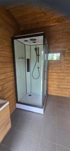 a glass shower in a room with a wooden wall at Mäe Puhkemaja in Rosma