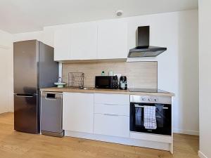 a kitchen with white cabinets and a stainless steel refrigerator at 8A - Le Nid in Saint-Rambert-dʼAlbon +8 photos