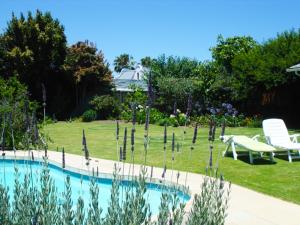 a swimming pool in a garden with two chairs and a table at Francolin's Rest Guest Suite in Sweet Valley +8 photos