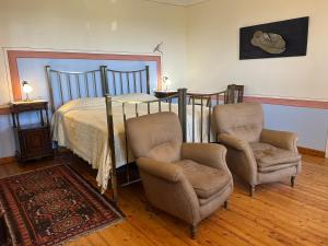 a bedroom with a bed and two chairs at Casa Molisso in Montegrosso dʼAsti