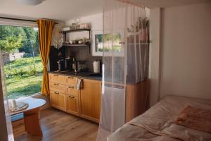 a bedroom with a bed and a kitchen with a window at Statek ráj Netvořice, Tiny house and Farm Experience in Netvořice