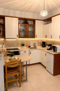 a kitchen with white cabinets and a table at HOUSE WITH GARDEN Netflix in Néa Kerasiá