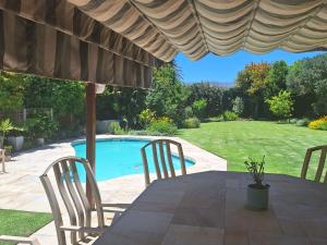 a table and chairs under an umbrella next to a pool at Francolin's Rest Guest Suite in Sweet Valley