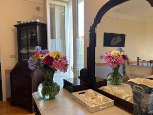 two vases with flowers on a table in front of a mirror at Casa Molisso in Montegrosso dʼAsti