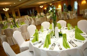 a dining room with white tables and chairs with green napkins at Seehotel Ecktannen in Waren