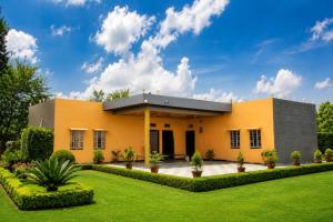 a yellow house with a green yard at Sand Dunes Stay in Bagru