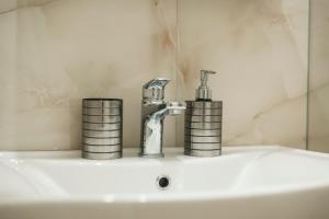 a bathroom sink with a faucet and two cups on it at Lotus Apartments in Vlorë +177 photos