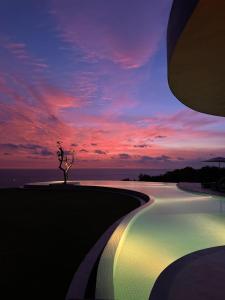 a swimming pool with a sunset in the background at Nya Uluwatu in Uluwatu