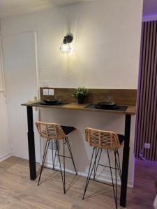 a counter with two stools and a counter top with a table at Le Nid douillet- Studio Chic au cœur Issoire in Issoire