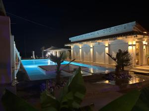 a swimming pool in front of a building at night at Borbara Apartman in Pázmándfalu