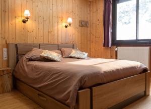 a bed in a bedroom with wooden walls and a window at Maison cosy à Cauterets avec vue sur les montagnes et jardin in Cauterets