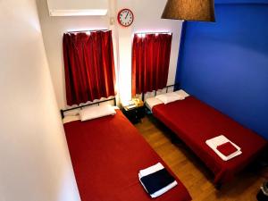 two beds in a room with red curtains and a clock at Guesthouse LuLuLu 無料朝食&夕食ｶﾚｰ付き ﾛｰｿﾝ隣 街まで電車8分 in Kochi