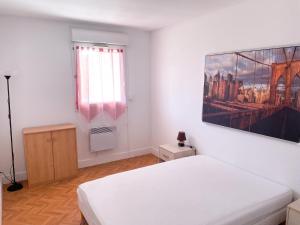 a white room with a bed and a picture on the wall at Appartement moderne à Fréjus, 60 m², piscine partagée in Fréjus