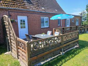 a wooden deck with a table and an umbrella at Bauernhof Angelika Schulze Pellworm in Pellworm