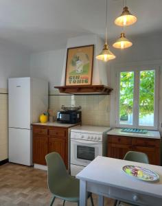 a kitchen with a white refrigerator and a table with chairs at Maison CÔTE OUEST in Labenne
